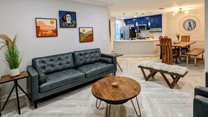 Ein modernes Wohnzimmer mit einer Ledersofa, einem Holztisch und einem Essbereich mit Holzstühlen und einer Bank.