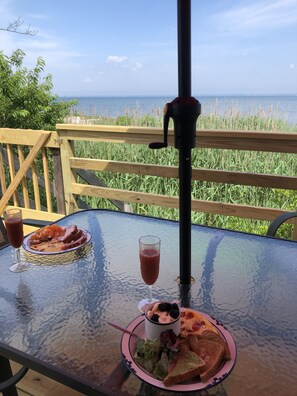 Ein Tisch mit Speisen und Getränken auf einer Terrasse mit Blick auf ein Gewässer.