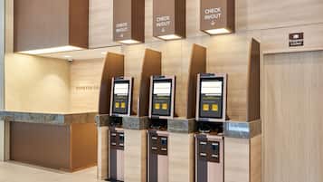 A check-in/out station with digital kiosks and a baggage locker.