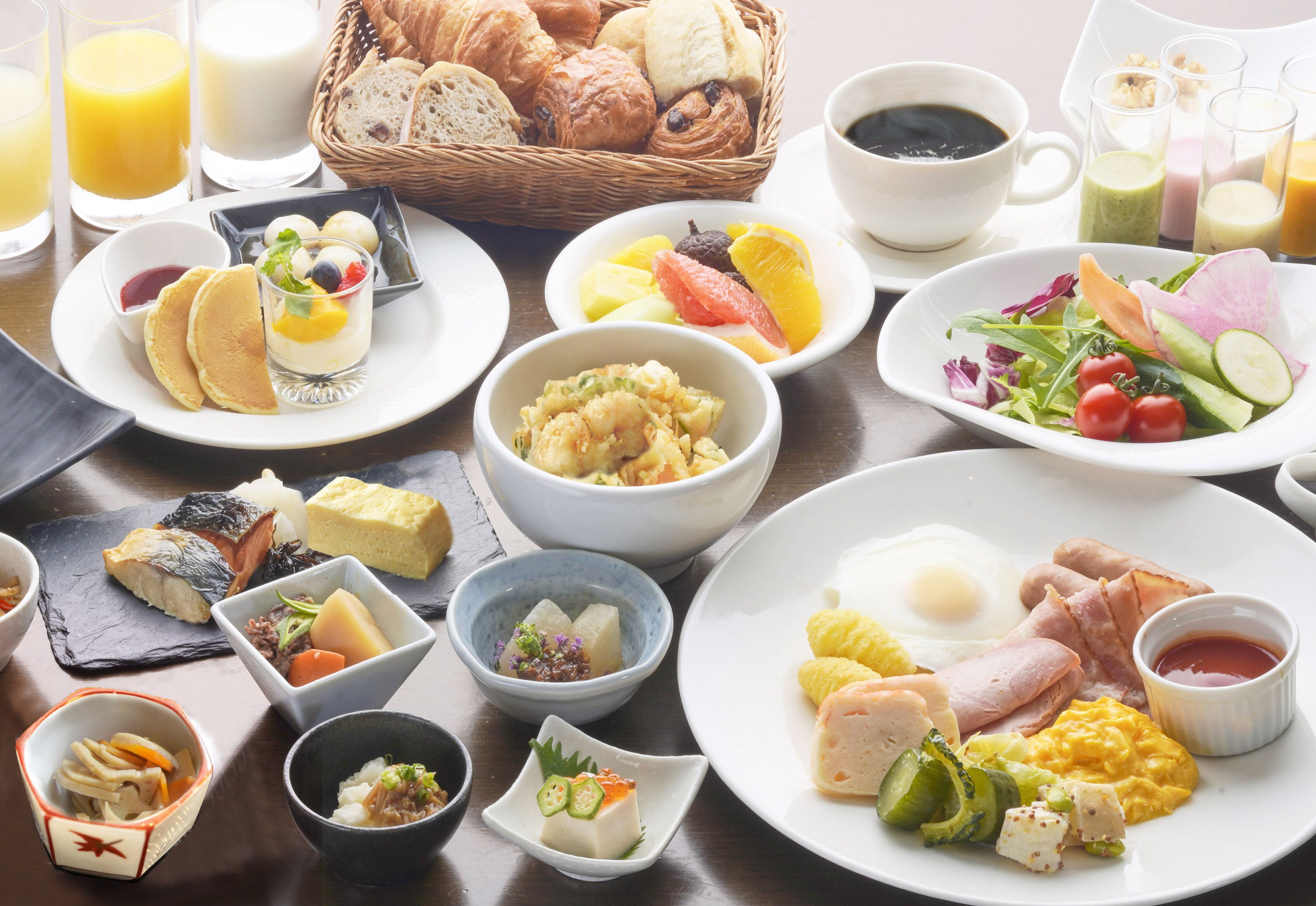 A variety of breakfast dishes including eggs, ham, and pastries, arranged on a table.