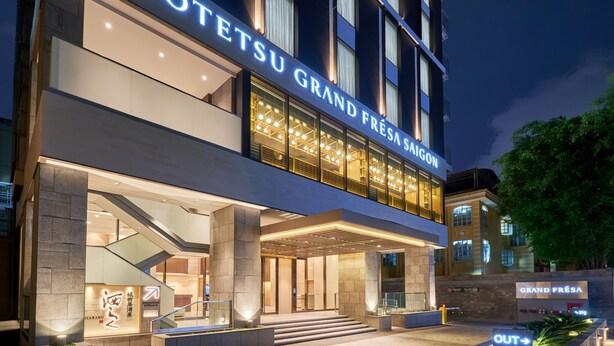 The exterior of Sotetsu Grand Fresa Saigon hotel with illuminated signage, a modern facade, and a well-lit entrance area. - Sotetsu Grand Fresa Saigon (Ho Chi Minh City)