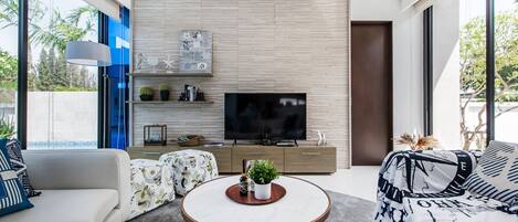Una sala de estar moderna con televisor de pantalla plana, pared de paneles de madera y ventanas amplias.