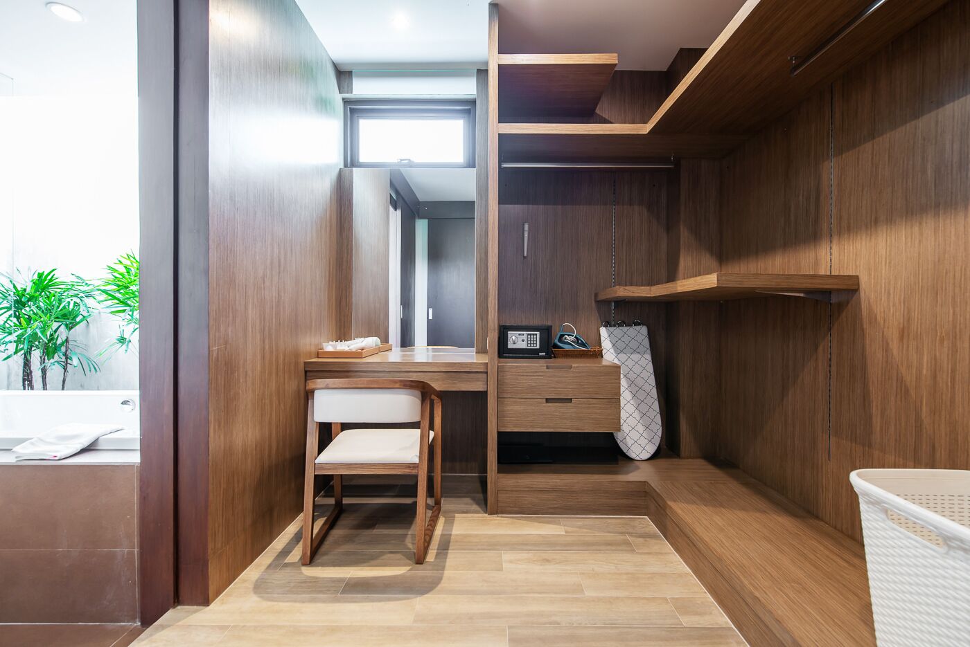 A modern bathroom with a wooden vanity, a chair, a towel rack, and a shower area.