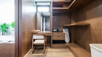 A modern bathroom with a wooden vanity, a chair, a towel rack, and a shower area.