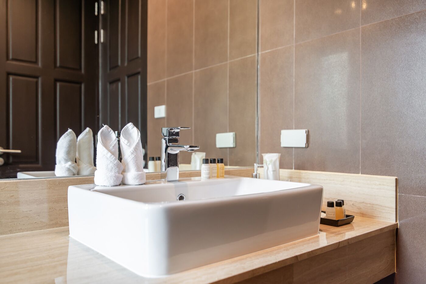A modern bathroom with a large white sink, dark wooden cabinets, and a mirror.