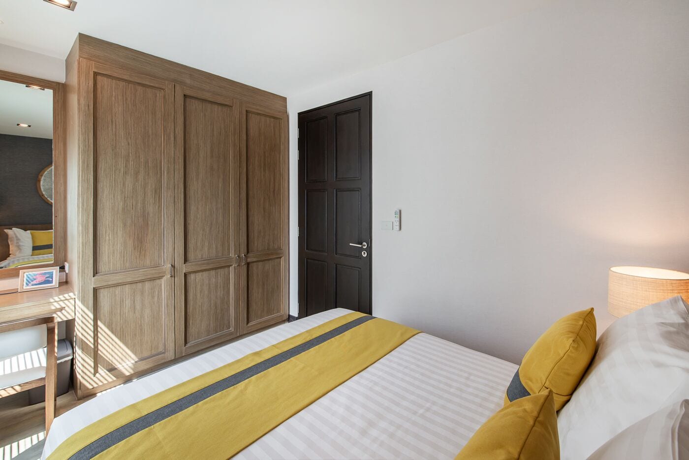 Een slaapkamer met een bed, een kledingkast, een deur en een bedlampje.