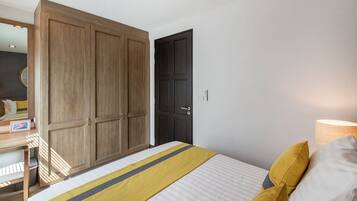 Een slaapkamer met een bed, een kledingkast, een deur en een bedlampje.