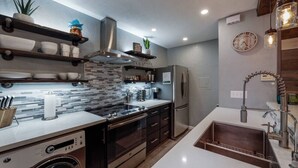 Una cocina moderna con horno empotrado, electrodomésticos de acero inoxidable y una isla grande con fregadero.