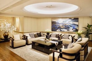 A spacious living room with a large sofa set, a coffee table, and a painting on the wall. - Xinxing Jingming Hotel (Ninghai)