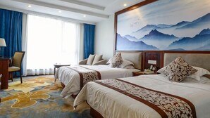 A hotel room with two beds, a desk, a chair, a large window with curtains, and a mountain landscape painting on the wall. - Xinxing Jingming Hotel (Ninghai)