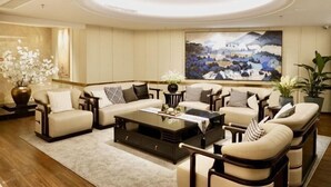 A modern living room with a large painting, a sofa set, and a coffee table. - Xinxing Jingming Hotel (Ninghai)