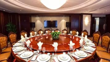 Un salón de conferencias con una mesa redonda, sillas y una pantalla de televisión.