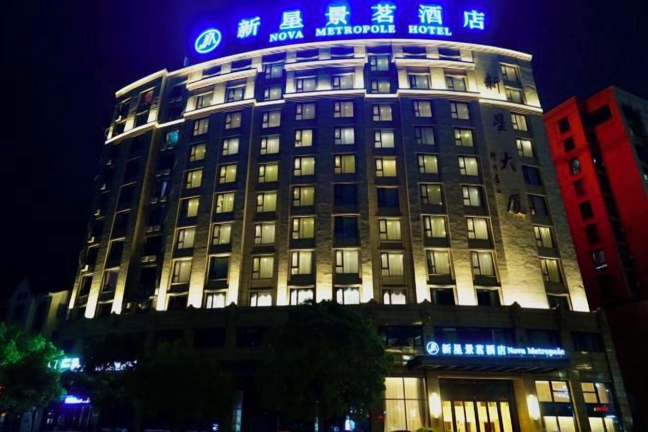 A hotel with a curved facade, multiple floors, and illuminated signage.