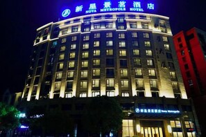 A hotel with a curved facade, multiple floors, and illuminated signage. - Xinxing Jingming Hotel (Ninghai)
