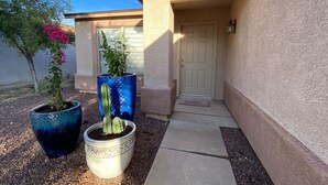 A building entrance with a door, a pathway, and two potted plants. - Near Kino / Fenced / Outdoor Living / 3BR & 2BA (Tucson)