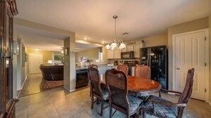 A spacious kitchen with a dining area, featuring a large wooden table and wicker chairs, a refrigerator, and a microwave. - Near Kino / Fenced / Outdoor Living / 3BR & 2BA (Tucson)