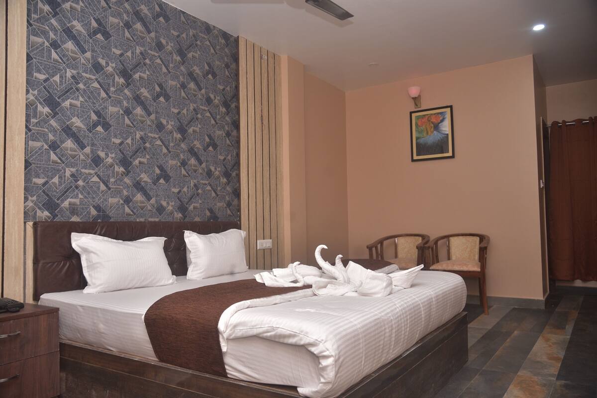 A hotel room with a bed, a nightstand, a chair, and a painting on the wall.