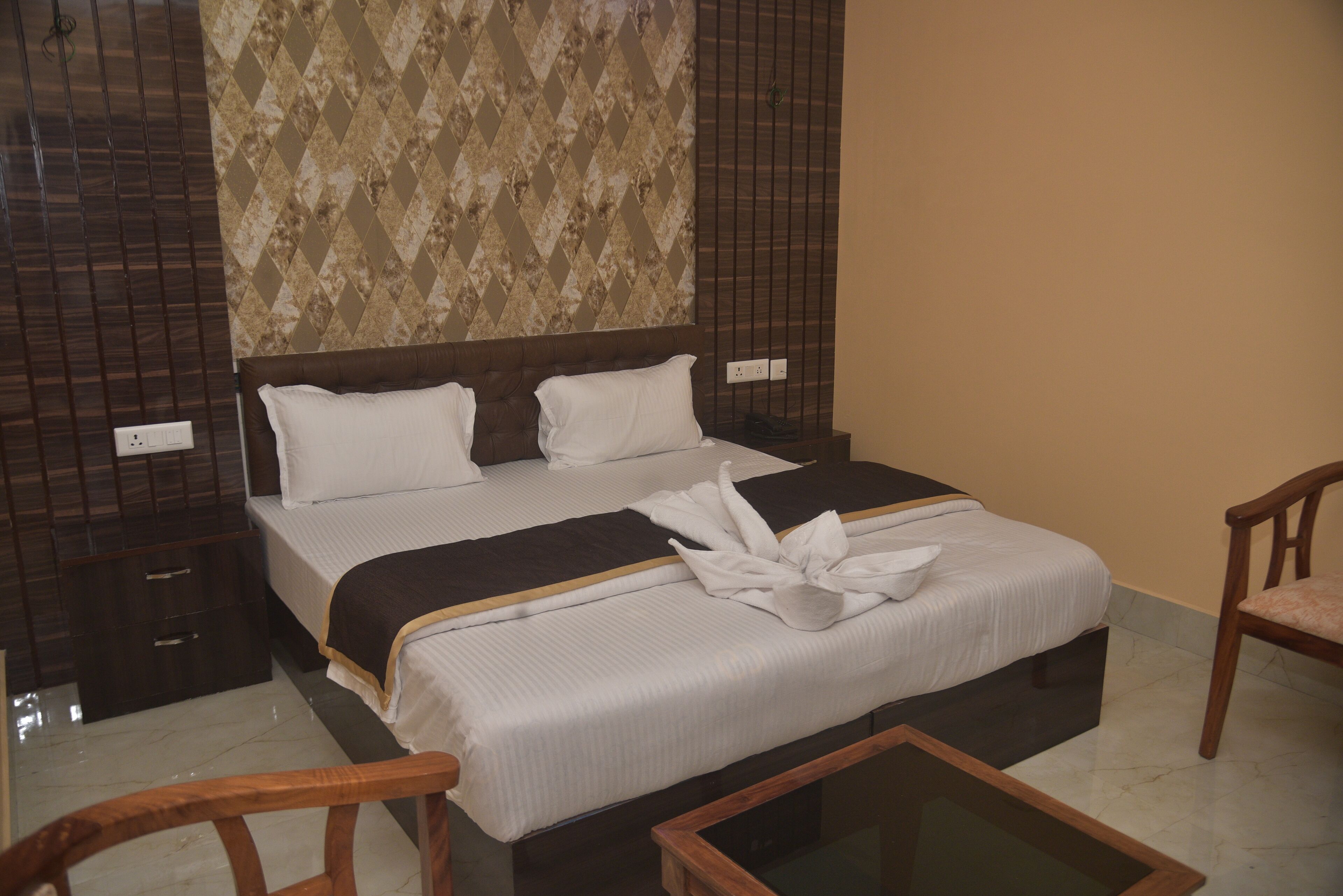 A neatly made bed with a white and brown bedspread, a wooden headboard, and a wooden chair with a cushion.