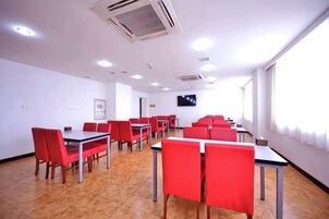 Un salón de conferencias con mesas, sillas, un televisor de pantalla plana y ventanas.