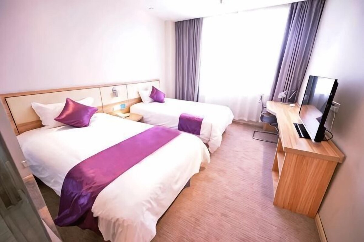 A hotel room with two beds, a desk with a computer, and a TV.