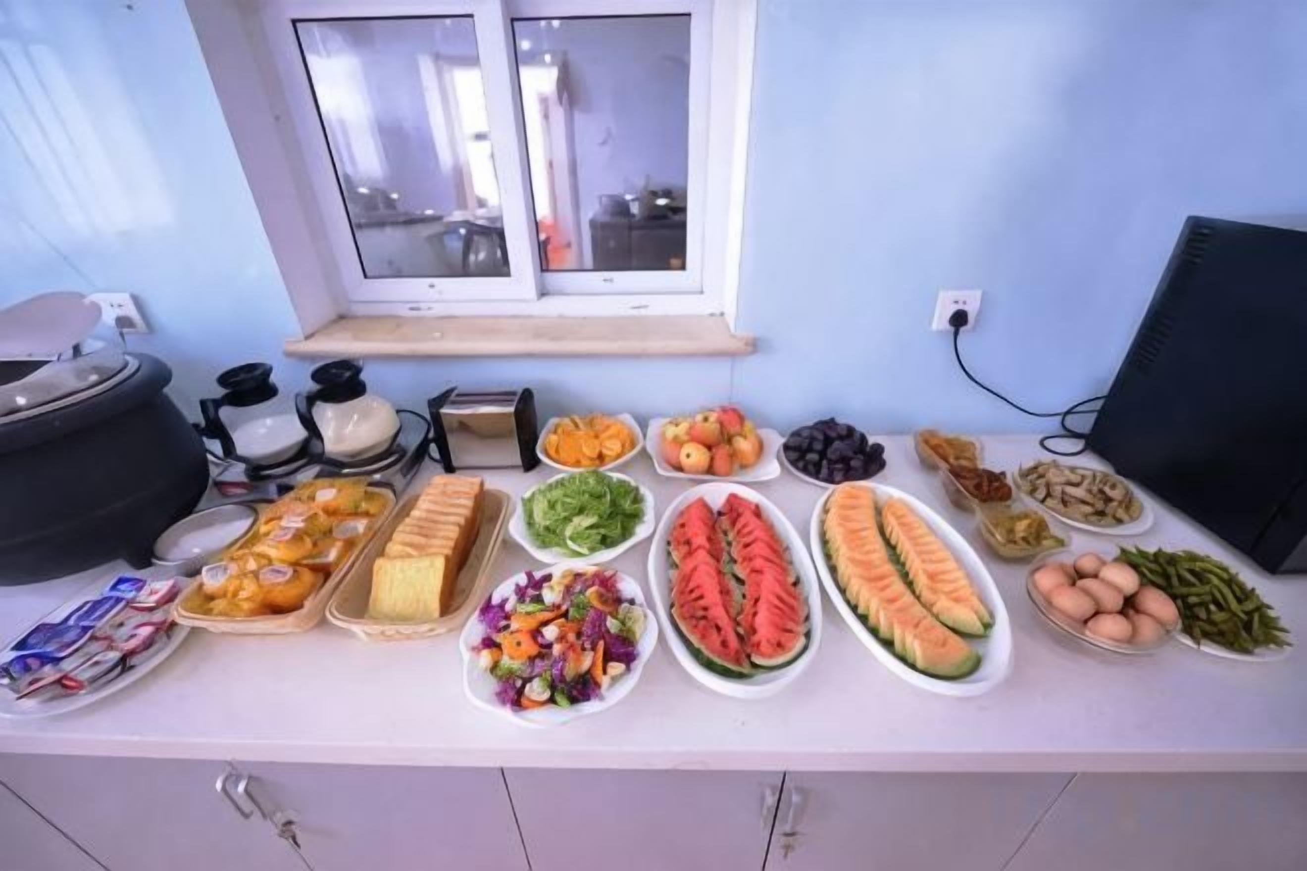 A buffet table with various food items and a window in the background.