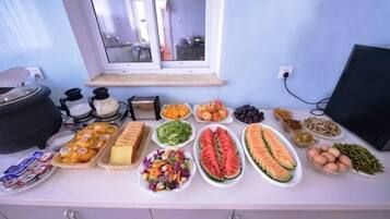 A buffet table with various food items and a window in the background.