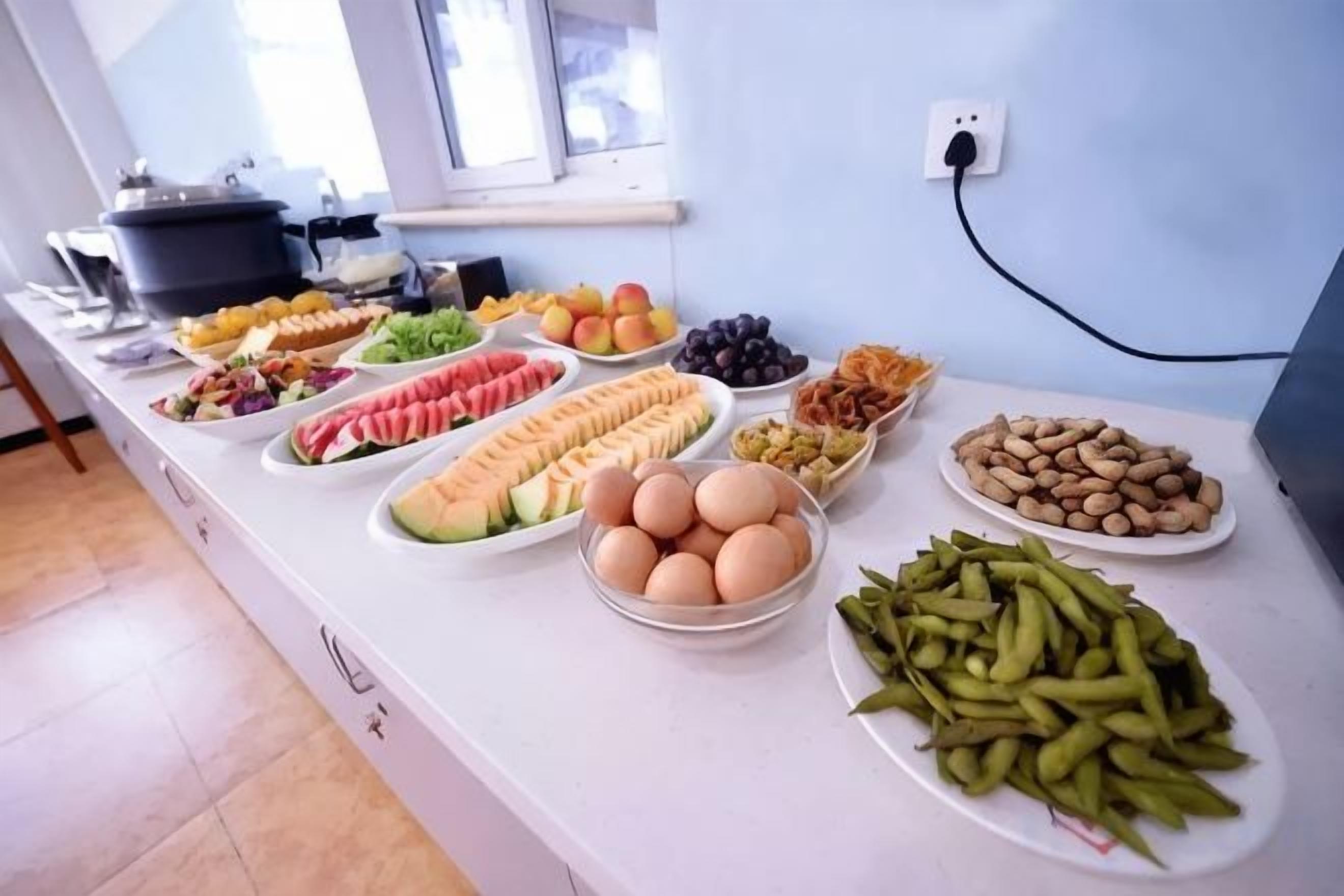 Une table de buffet proposant divers aliments, notamment des fruits, des légumes et des œufs.