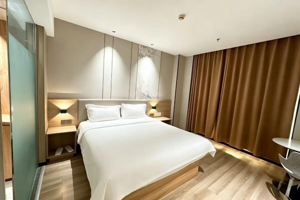 Habitación de hotel con una cama grande, mesitas de noche, un escritorio y vistas al exterior.