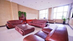 A spacious living area with leather sofas, a coffee table, and a large window providing natural light. - Lejia Hotel (Bazhou Shengfang International Furniture Expo City) (Bazhou)