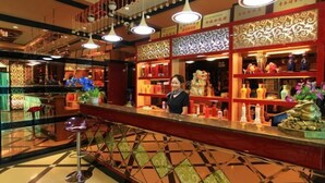 A bar area with a checkered floor, a bartender, and shelves with various bottles and decorative items. - Jinta Hotel (Jinta)