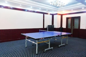A room with a ping pong table, a projector screen, and a carpeted floor.