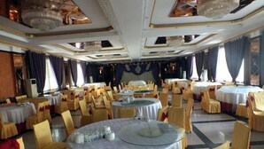A banquet hall with round tables, chairs, and chandeliers. - Jinta Hotel (Jinta)