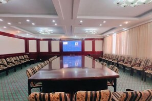 A conference room with a long table and chairs, a projector screen, and a large window with curtains. - Jinta Hotel (Jinta)