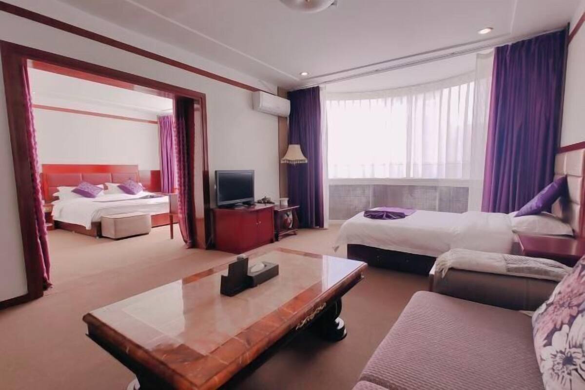 A hotel room with two beds, a TV, a coffee table, and a sofa.