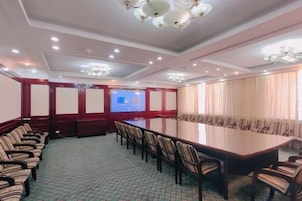 Un salón de conferencias con una mesa larga, sillas y una pantalla para proyector.