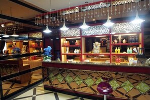 A well-lit bar area with shelves of bottles and a decorative ceiling. - Jinta Hotel (Jinta)