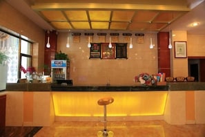 A hotel reception area with a counter, a bar stool, and a menu board. - Jinta Hotel (Jinta)