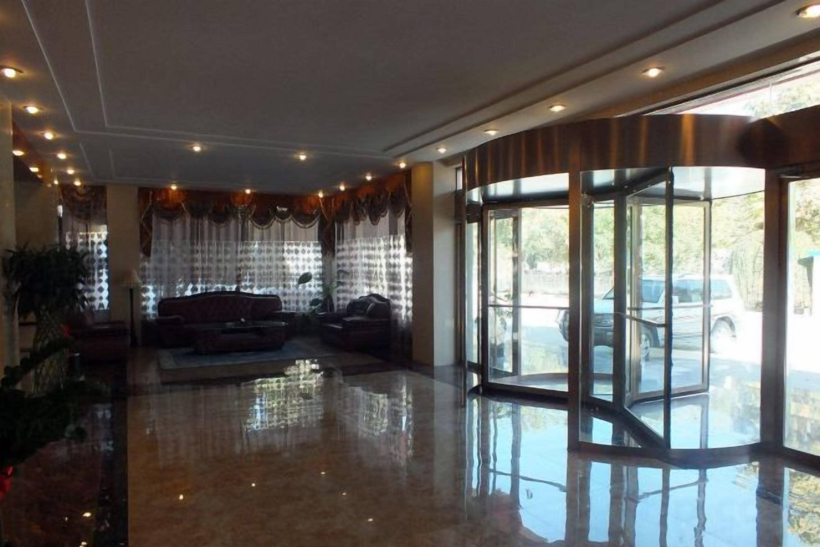 Een hotel lobby met een zithoek, een glazen ingang en uitzicht op buiten.