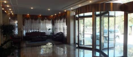 Un hall de hotel con zona de estar, entrada de cristal y vistas al exterior.