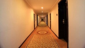 A long, narrow hotel hallway with carpeted floors and doors on both sides leading to rooms. - Jinta Hotel (Jinta)