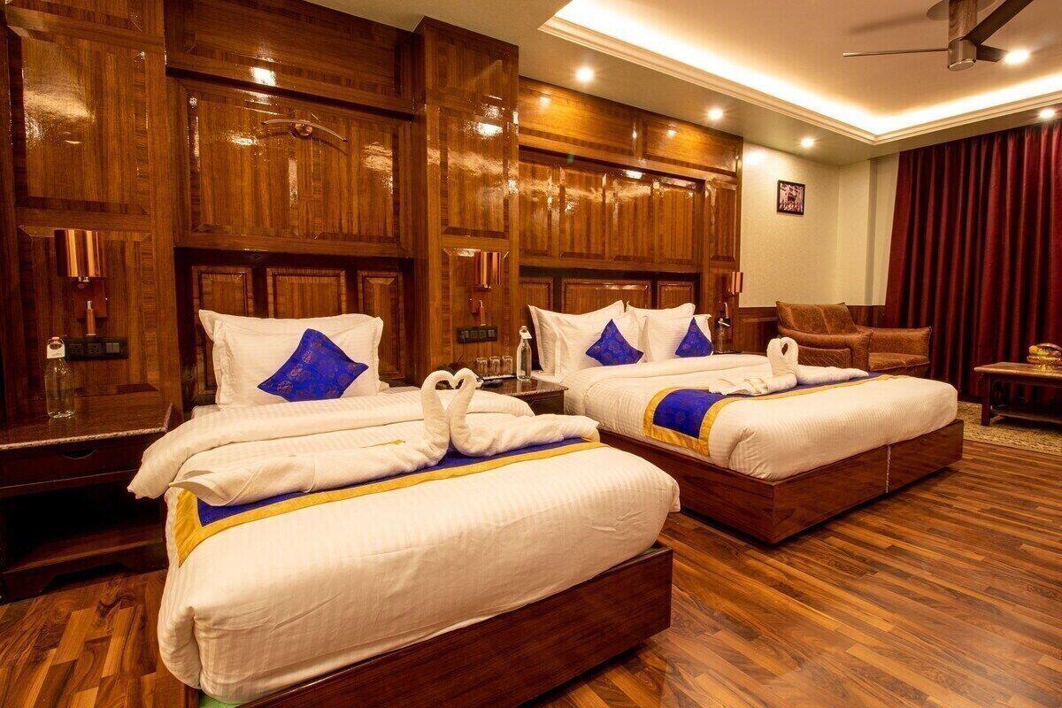 Habitación de hotel con dos camas, paneles de madera, ventilador de techo y una cortina roja.