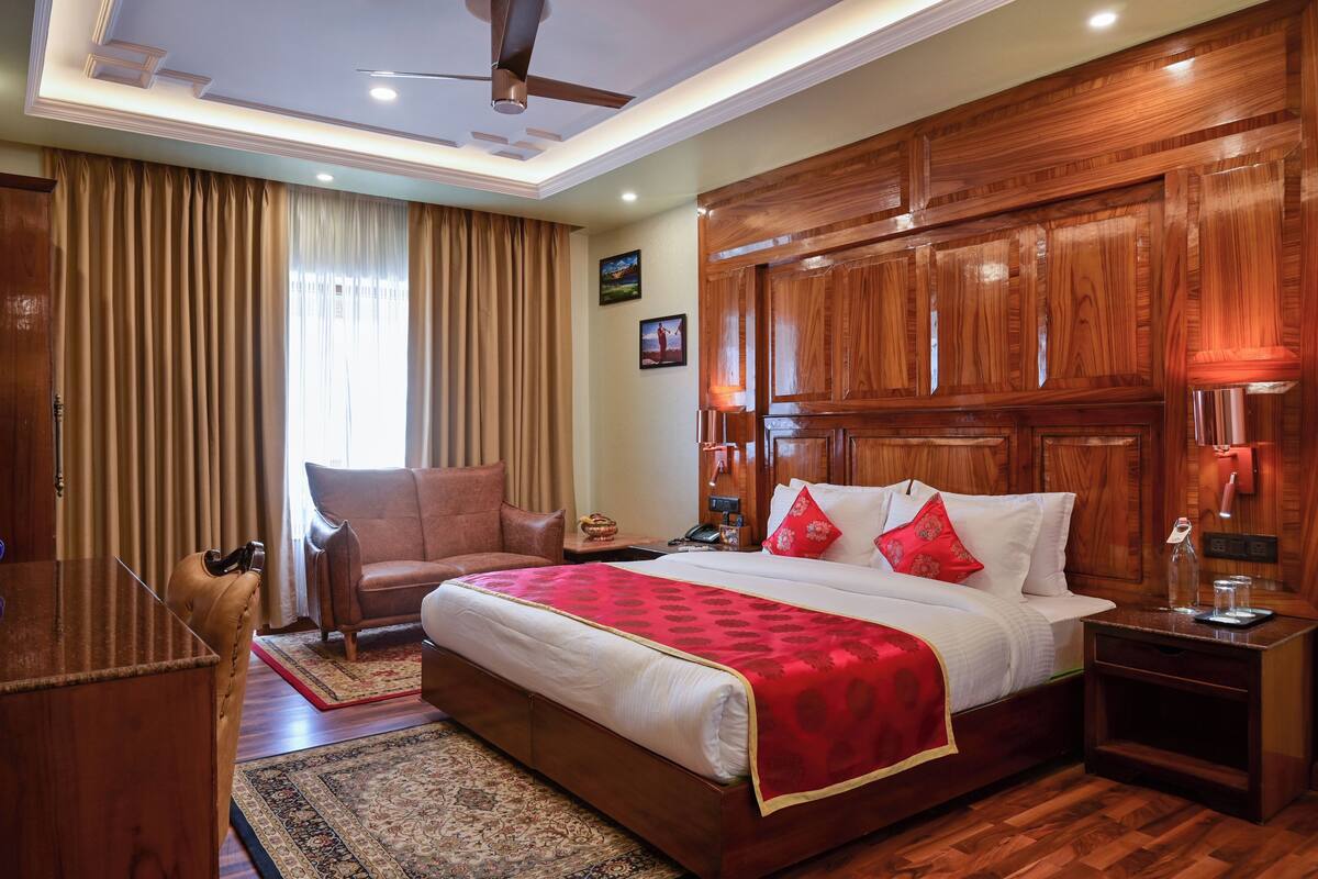 Habitación de hotel elegante con una cama grande, cabecera de madera, un escritorio y una silla.