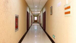 A long, narrow hallway with a polished floor, doors on both sides, and emergency exit signs on the walls. - Taidawenquanbinguan (Yongqing)