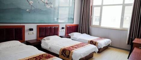 A hotel room with three beds, a large window, and a wall painting.