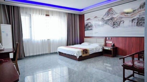 A hotel room with a bed, a desk, a chair, a nightstand, and a painting on the wall. - Taidawenquanbinguan (Yongqing)