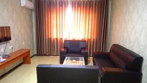 A living room with a sofa, a coffee table, and a TV on a stand. - Taidawenquanbinguan (Yongqing)