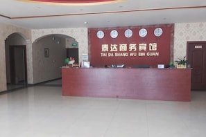 A reception desk with a sign in a foreign language, a clock, and a door to the right. - Taidawenquanbinguan (Yongqing)
