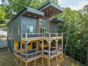 A multi-level wooden cabin with a balcony, large windows, and a deck area.