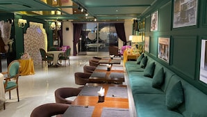 A modern restaurant with a green color scheme, featuring a long dining table with cushioned seating and a sofa. - Sabina Boutique Hotel 3 (Ho Chi Minh City)