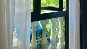 A window with a view of a building and greenery. - Sabina Boutique Hotel 3 (Ho Chi Minh City)